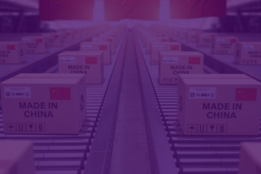 Homem de negócios sorrindo ao analisar gráficos de importação da China com pacotes e contêineres ao fundo.