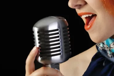 Mulher cantando em palco, representando o Curso de Canto Iara Negrete - Além da Voz